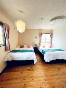 a bedroom with two beds and a chandelier at 白浜リゾート・源 in Kanayama