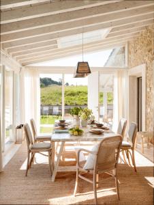 a dining room with a white table and chairs at Cuadra rehabilitada, piscina climatizada, Comillas in Lamadrid