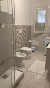 uma casa de banho com 2 WC e uma cabina de duche em vidro. em Casa Vacanza Sicily House em Gaggi