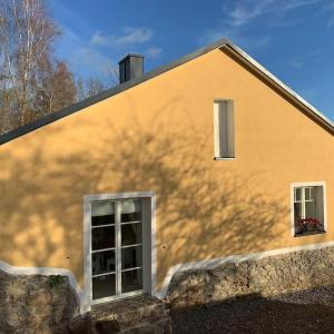 Casa amarilla con 2 ventanas y pared de piedra. en Cottage Knezice, en Petrovice