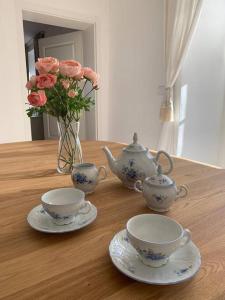 una mesa de madera con dos tazas de té y un jarrón con flores en Cottage Knezice, en Petrovice