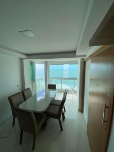 a dining room with a table and chairs and the ocean at Apartamento de frente para o mar Praia do Morro Guarapari in Guarapari