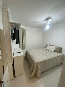 a small bedroom with a bed and a television at Apartamento de frente para o mar Praia do Morro Guarapari in Guarapari