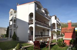 a white building with two chairs in the yard at Apartments in Beautiful Split in Podstrana