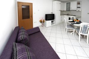 a living room with a purple couch and a kitchen at Apartments in Beautiful Split in Podstrana