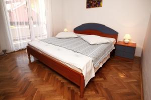 a bedroom with a bed and a wooden floor at Apartments in Beautiful Split in Podstrana
