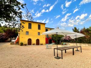 a yellow building with a table and an umbrella at Donna Vittori - Borgo Agricolo in Paliano