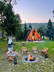 een tent met stoelen en een vuurplaats in het gras bij Domek nad Potokiem w Beskidach in Rajcza