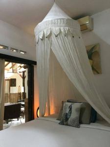 a bedroom with a bed with a white canopy at Frangipani Garden Villa in Senggigi 