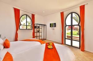 two beds in a room with two windows at DOMAINE DU DOUAR in Marrakech