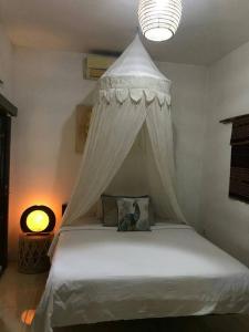 ein weißes Bett mit Baldachin in einem Schlafzimmer in der Unterkunft Frangipani Garden Villa in Senggigi 