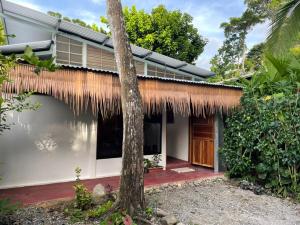 a house with a thatched roof and a tree at Casita Coco in Puerto Limón