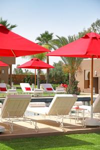a group of chairs and umbrellas next to a pool at DOMAINE DU DOUAR in Marrakech
