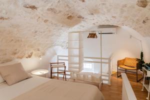 a bedroom with a bed in a room with a wall covered in plaster at Casa Vico Melles in Ostuni