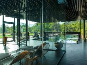 Habitación con paredes de cristal, sillas y mesa. en Manna Resort, en Montagna
