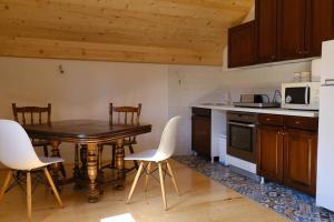 a kitchen with a wooden table and white chairs at Vig in Njegovuđa