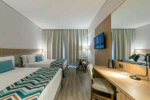 ein Hotelzimmer mit 2 Betten und einem Schreibtisch in der Unterkunft Japy Golf Resort Hotel in Cabreúva