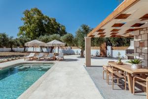 a patio with a pool and a table and chairs at Bedrock beachside villa with private pool in Vasilikos