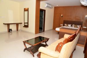 a living room with a couch and a bed at Sanjose Residency in Virajpet