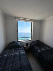a bedroom with two beds and a large window at Departamento 3D2B Condominio Altos de Huayquique in Iquique