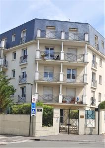 a large white building with balconies on a street at Nid douillet plein de charme avec Parking gratuit in Chantilly