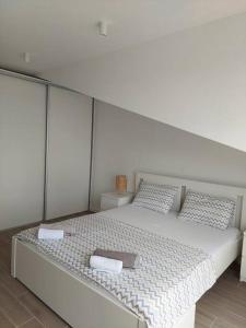 a white bed with two pillows and a box on it at Mini Condos® 28DL - 1 bed condo, 2 min to the sea in Tivat