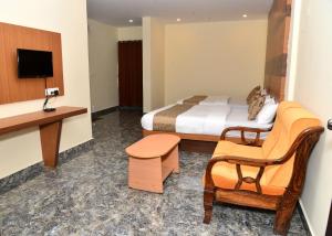 a hotel room with a bed and a chair at Sanjose Residency in Virajpet