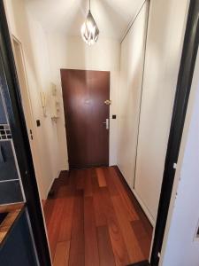 a hallway with a brown door and wooden floors at Nid douillet plein de charme avec Parking gratuit in Chantilly