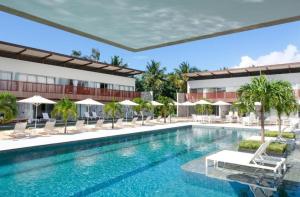 a pool at a hotel with chairs and umbrellas at Flat Île de Pipa Resort - Centro in Pipa