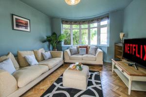 ein Wohnzimmer mit einem Sofa und einem TV in der Unterkunft Elegant 3-Bed Home, West Bridgford & Large Garden in Nottingham