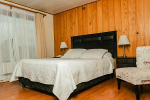 a bedroom with a large bed and a chair at Hotel Terrazas del Lago in Puerto Varas