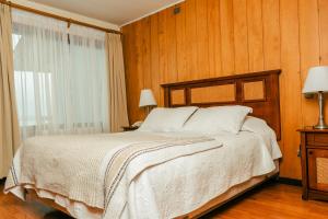 Schlafzimmer mit einem großen Bett und Holzwänden in der Unterkunft Hotel Terrazas del Lago in Puerto Varas
