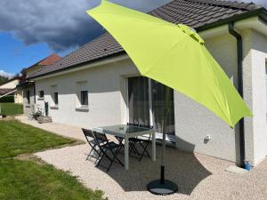 a yellow umbrella on a table in front of a house at Maison de la forêt in Dole