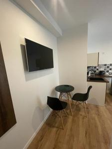 een kamer met een tafel en twee stoelen en een televisie aan de muur bij Noclegi u Anny in Rzemień