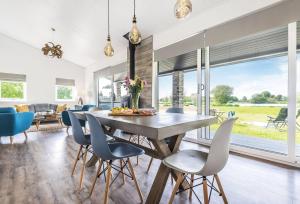 a dining room and living room with a table and chairs at Stunning 3 Bed Lodge, Log Burner & Hot Tub with Lake View - Lakeside Lodge in Sturminster Marshall