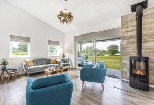 sala de estar con sillas azules y chimenea en Stunning 3 Bed Lodge, Log Burner & Hot Tub with Lake View - Lakeside Lodge, en Sturminster Marshall