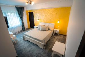 1 dormitorio con cama y pared amarilla en Pensiunea Alessia Soveja en Soveja
