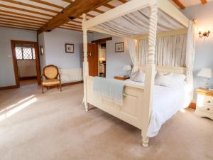 a bedroom with a white canopy bed and a chair at The Old Carthouse in Nantwich