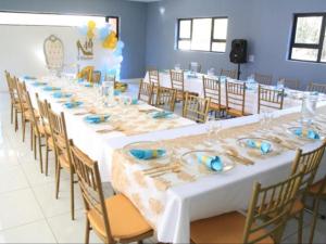 un lungo tavolo con tovaglie bianche e piatti blu di Masili Boutique Hotel a Louis Trichardt