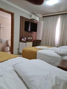 a hotel room with two beds and a television at San Marino Palace Hotel in Guarapuava