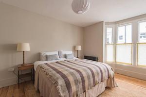 Dormitorio blanco con cama con manta a rayas en Ollerton, en Kent
