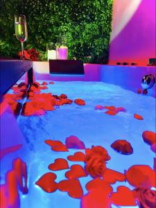 a pool of water with red flowers and a glass of wine at Suite in the City - Standing Hyper-centre JACUZZI CLIM WIFI in Montpellier