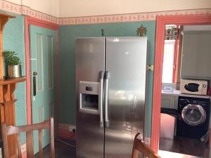 a stainless steel refrigerator in the corner of a kitchen at Rooms or Entire City House 6min drive to Stadium of Light in Sunderland
