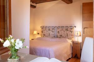 SantʼAppiano的住宿－Al Gelso Bianco，一间卧室,配有一张床,桌子上放着花瓶