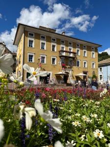 un bâtiment avec un champ de fleurs devant lui dans l'établissement Romantic Hotel Excelsior, à Cavalese