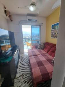 sala de estar con sofá rojo y TV en Quarto privativo em Apto Barra com Vista - com anfitrião, en Río de Janeiro