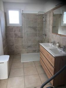 La salle de bains est pourvue d'une baignoire, d'un lavabo et d'une douche. dans l'établissement Maison les coquelicots, à Garennes-sur-Eure