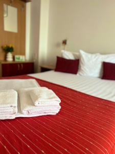 two beds with white towels on a red blanket at Pensiunea Elena in Timişoara