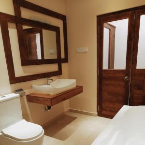 a bathroom with a sink and a toilet and a mirror at Luxury Beach Apartment in Hambantota