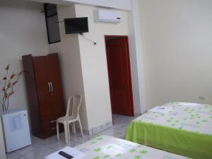 a bedroom with a bed and a chair and a tv at Casa Linda II in Iquitos